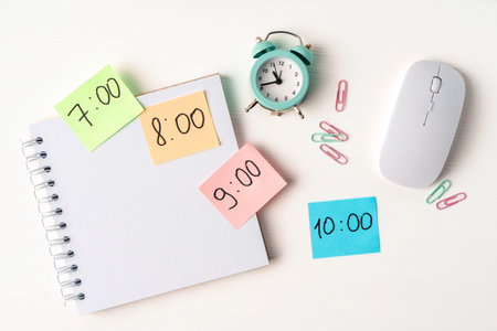 Color notes with time on desktop with notepad, alarm clock. Copy space. The concept of planning the...