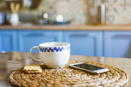 A mug of tea on the kitchen table, the blurry facade of the kitchen in the background. The concept of office or relaxation at homeの写真素材