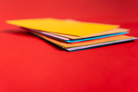 A stack of colored envelopes on a red backgroundの写真素材