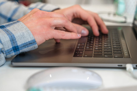 Men's hands typing on a laptop keyboard, a business concept of working in the office as a programmer...