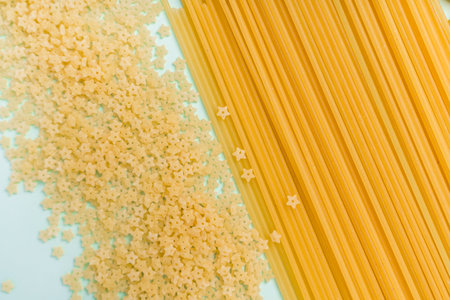 Different types of pasta from wheat varieties laid out in a line on a light wine background, copy...