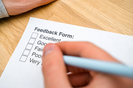 A questionnaire with answer options for the feedback form. A man ticks a box on a white paper while sitting at a wooden table. Checking the form of the check box.の写真素材