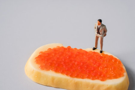 Miniature people, a businessman standing on a caviar sandwich, the concept of wealth and successの写真素材