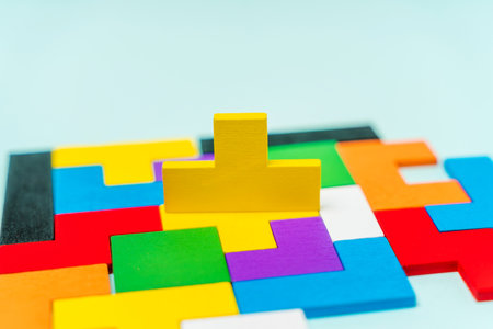 Geometric shapes made of wood in different colors on a blue background with a missing shape,...