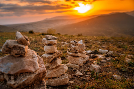 A stone stack with balanced stones on a blurry background of mountains at sunsetの写真素材