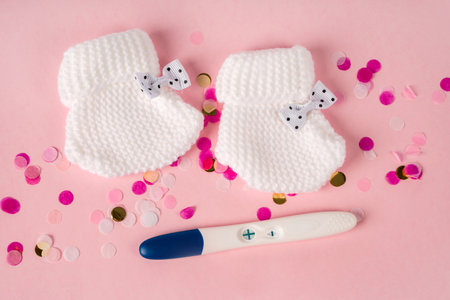 A positive pregnancy test and baby booties on a background. Waiting for the baby.