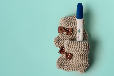 A positive pregnancy test and baby booties on a background. Waiting for the baby.の写真素材