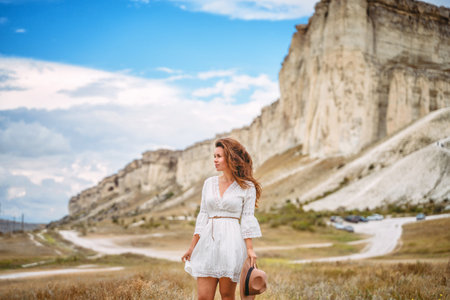 A beautiful young woman in a white dress at the foot of a White Rock in the Crimea. A beautiful concept of purity and magic.の写真素材