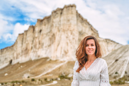 A beautiful young woman in a white dress at the foot of a White Rock in the Crimea. A beautiful concept of purity and magic.の写真素材