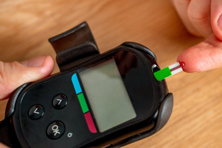 A man at home uses a glucose meter to measure blood glucose. Piercing a finger with a needleの写真素材