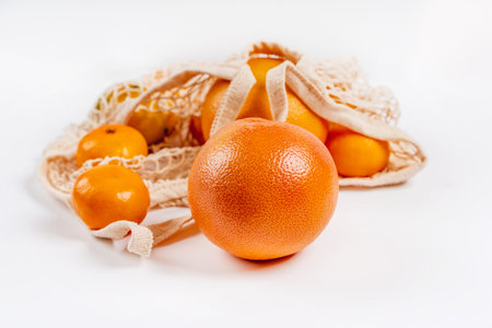 Citrus fruits in a cotton eco-bag on a white background. The concept of a healthy lifestyle and freshnessの写真素材
