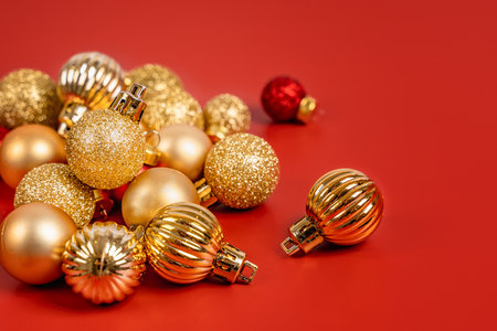 Red and gold Christmas balls lie on a red background, a beautiful minimalistic background for Christmas and New Yearの写真素材