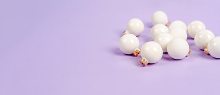 White Christmas balls lie on a purple background, a beautiful minimalistic background for Christmas...