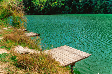 Beautiful summer landscape in the mountains with an azure lake surrounded by forest and a wooden pierの写真素材