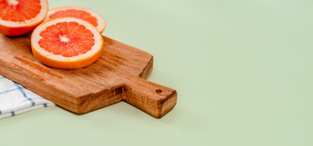 Grapefruit slices on a wooden board on a green background. The concept of healthy nutrition, vitamin C, healthy lifestyleの写真素材