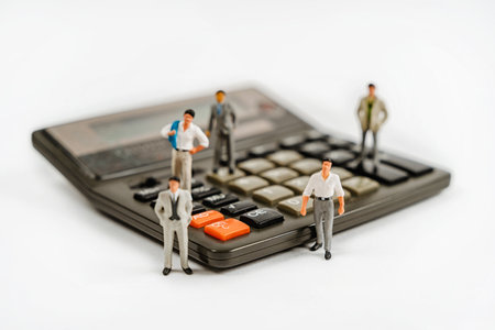 Miniature figures of businessmen stand on a calculator to calculate profits. The concept of business and making moneyの写真素材