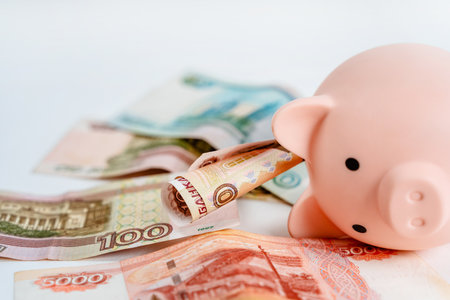 Piggy bank and Russian banknotes on a white background. The concept of accumulation and storage of moneyの写真素材