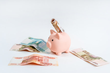 Piggy bank and Russian banknotes on a white background. The concept of accumulation and storage of moneyの写真素材