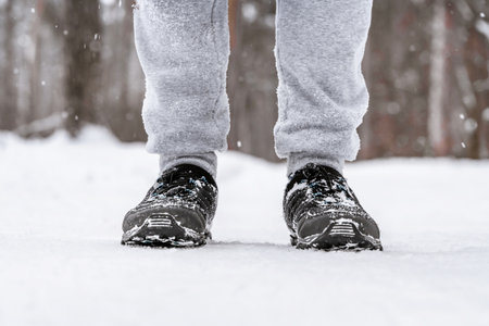 Men's feet in sports shoes in the snow in a snowy forestの写真素材