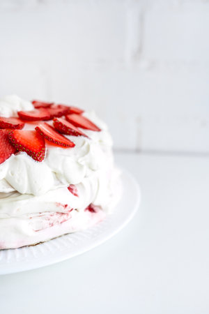Delicious cake with cream cheese and strawberries. Beautiful serving on a white brick background