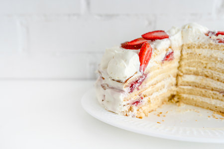 Delicious cake with cream cheese and strawberries. Beautiful serving on a white brick backgroundの写真素材