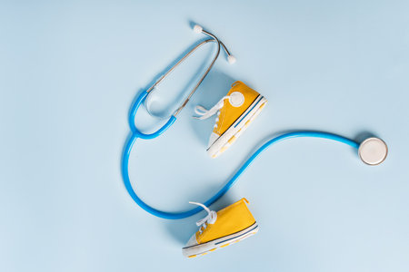 Children's shoes and a first aid kit with a thermometer and pills on a blue background. Space for text. The concept of children's health, treatmentの写真素材