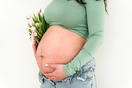 A beautiful young pregnant woman in a bright modern interior. Tender concept of motherhood, pregnancy and baby waitingの写真素材