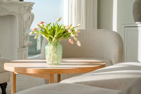 A bouquet of tulips in a beautiful vase at home in a bright modern interior on a wooden table. spring conceptの写真素材