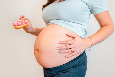Pregnant woman holding a donut, diet concept and gestational diabetes mellitus in pregnant womenの写真素材