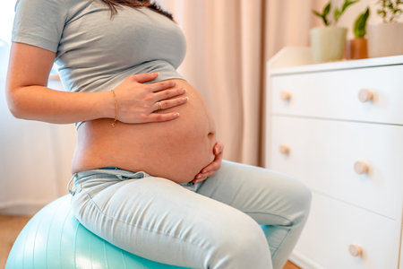 A pregnant woman is sitting on a gymnastic fitness ball. The concept of relaxation and a healthy body during pregnancyの写真素材
