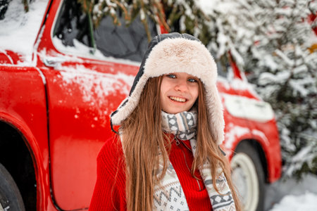 Winter portrait of a beautiful young woman in the red sweater and hat on the background of the carの写真素材
