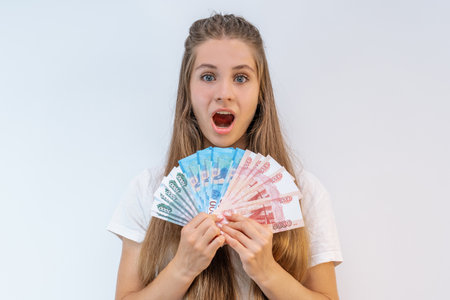 A young girl with ruble notes is joyful on an isolated white background. Saint Petersburg, Russia -...