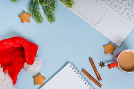 Christmas home office desk with a notebook, computer keyboard, Christmas balls, cocoa mug on blue background. Flat lay, top view.の写真素材