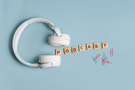 Top view on a blue background with wooden letters, the word podcast is laid out, flat lay with a notebook and headphonesの写真素材