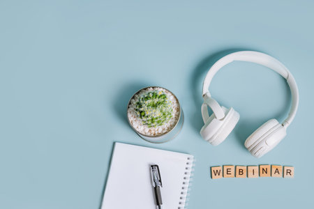 Top view of a blue surface with wooden letters, the word webinar is laid out, flat lay with a notebook and headphonesの写真素材