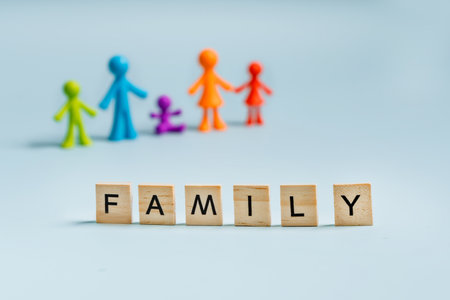 Multicolored figures of little men family on an isolated blue background, with the wooden letters "family" in the foregroundの写真素材