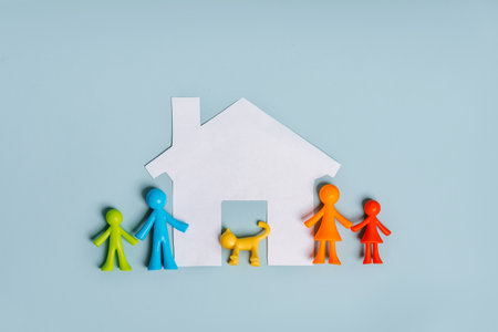 Multi-colored figurines of little men, a family on an isolated blue background with a paper houseの写真素材