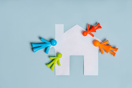 Multi-colored figurines of little men, a family on an isolated blue background with a paper houseの写真素材