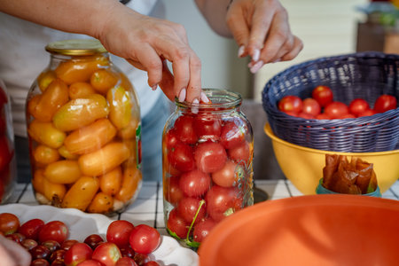 Preserving cherry tomatoes in glass jarsの写真素材