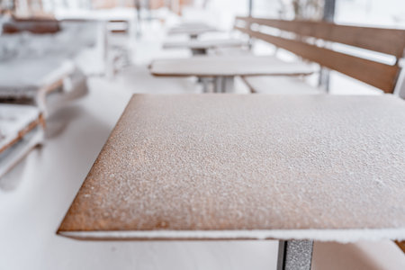 Snow-covered outdoor cafe with chairs and tables in winterの写真素材