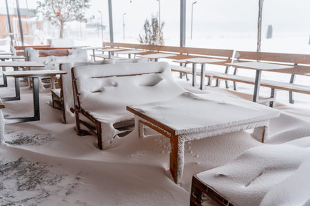 Snow-covered outdoor cafe with chairs and tables in winterの写真素材