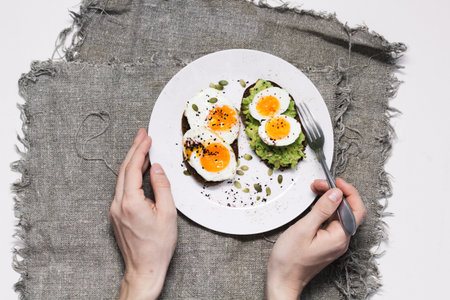sandwich with fresh vegetables, avocado, hard-boiled eggs and pumpkin seeds with olive oil and bread. healthy diet or vegetarian food on a white background. salad with yolks on toast. top view.の写真素材