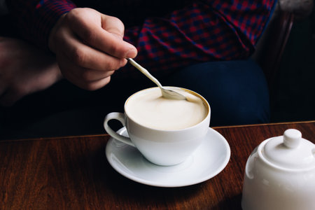 coffee in hands. woman relaxing near the window in a vintage restaurant. caffeine is invigorating. cappuccino in a glass.の写真素材