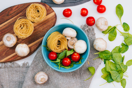 Fresh spinach and cherry tomatoes with mushrooms and pasta. Raw vegetable. natural plant leaf. healthy and vegetarian or organic bio food. top view. close upの写真素材