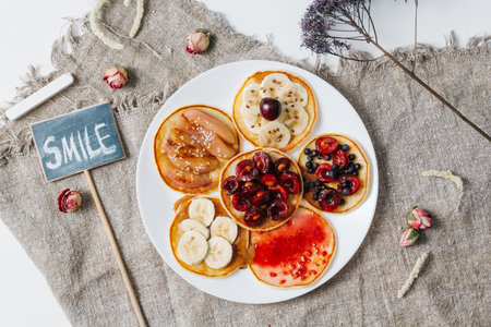 Baked pancakes or homemade cakes. On top is decorated with berries, fruits, honey and jam on rustic background. top view. close up. Chalk plaque with the inscription SMILEの写真素材