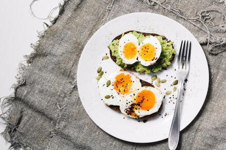 sandwich with fresh vegetables, avocado, hard-boiled eggs and pumpkin seeds with olive oil and bread. healthy diet or vegetarian food on a white background. salad with yolks on toast. top view.の写真素材