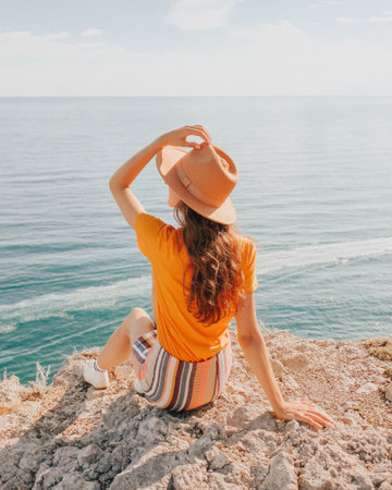 Beautiful girl in a hat on a summer vacation in the mountains on nature. Blue sky and sea.の写真素材