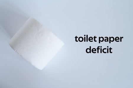 rolled white toilet paper on a white background and text toilet paper deficit. ofl font. flat lay, top viewの写真素材