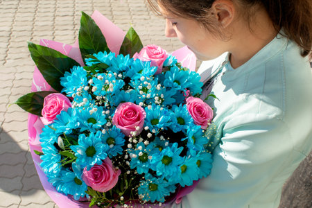 Young girl enjoys the flavor of bouquet of blue and rose flowers. Present for Birthday, Women 's day...