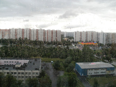Large drops on the background against the background of city buildings, gray sky and green treesの写真素材
